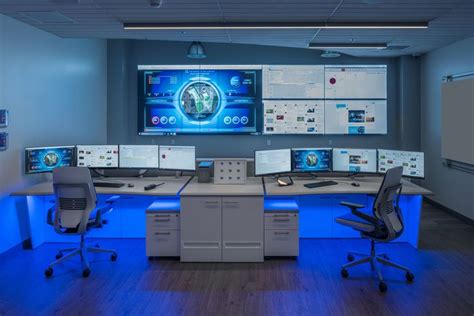 an office cubicle with multiple computer screens on the wall and desks ...