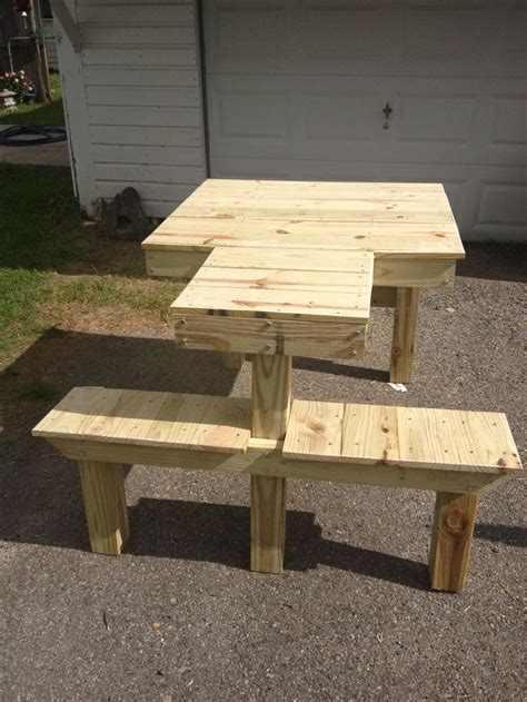 a wooden picnic table and benches in front of a garage