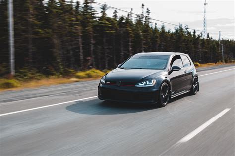 Sports car riding on paved road near forest in daytime · Free Stock Photo