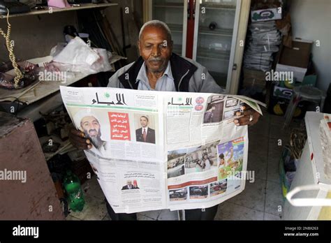 A Palestinian vendor reads the Al-Ayyam newspaper featuring photos of ...