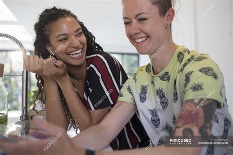 Happy young women friends laughing in kitchen — lifestyle, tattoo ...