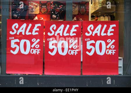 sale signs in display window of clothing store and people outside on ...