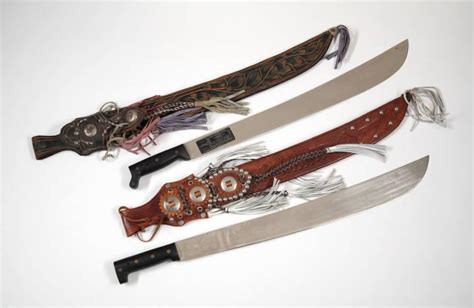 TWO MACHETE SWORDS WITH DECORATIVE LEATHER SHEATHS