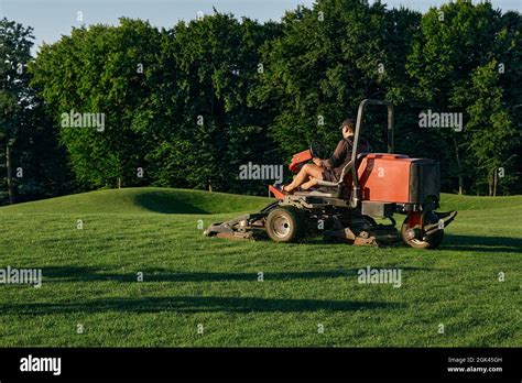 Greenkeeper. Golf course maintenance worker, cutting green grass Stock Photo - Alamy