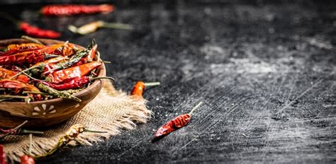 Premium Photo | Pods of dried chili peppers in a wooden plate on a napkin