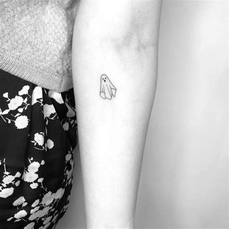 Minimalist ghost tattoo on the inner forearm.