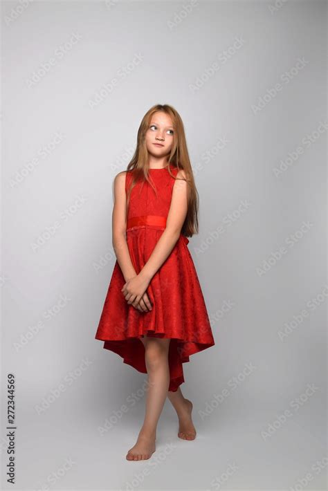 redhead teen girl in red dress in Studio in full length. The girl looks ...