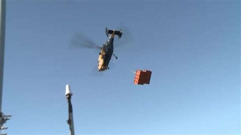 Tilting long shot of helicopter lifting container off of ship and flying off with it. - Stock ...