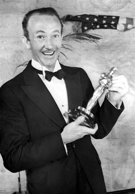 an old black and white photo of a man in a tuxedo holding his oscar award
