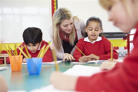 Teacher helping female pupil with writing - OTrack Pupil Tracking Software