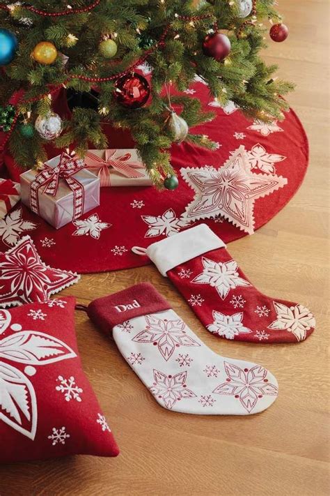 christmas stockings and gifts under a tree on the floor next to a red blanket with white snowflakes