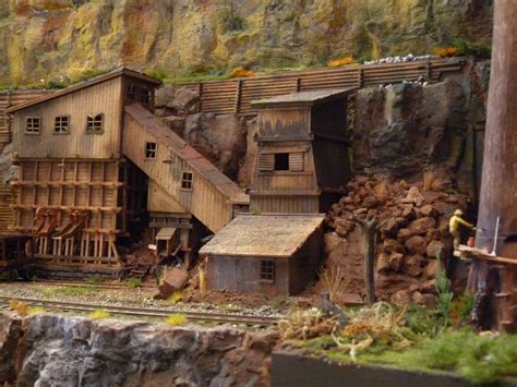 a model train set with wooden buildings and mountains in the backgroung area