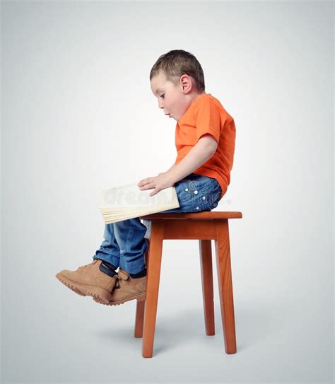 Child Sitting On A Chair With A Book Stock Photo - Image: 59952934