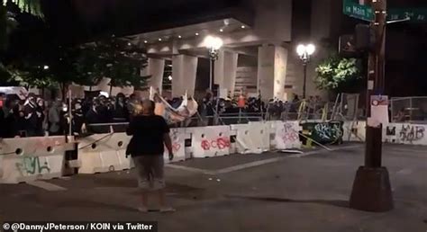 Protesters burn an American flag hanging outside Portland Justice Center and replace it with a ...