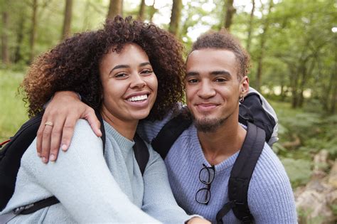 A young mixed race couple smiling to camera during a hike in a forest ...