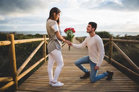 Man kneeling handing a bouquet of roses to a woman Photo | Free Download