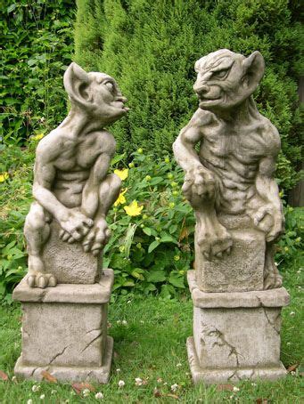 two gargoyle statues sitting in the grass