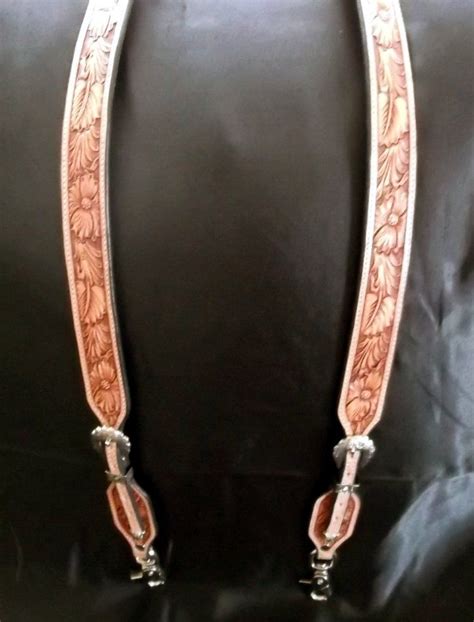 A pair of full floral tooled cowboy suspenders with silver buckles ...