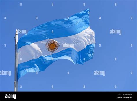 Argentinean flag on a clear blue sky background. Blue and white National symbol of Argentinean ...