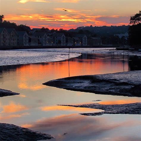 the sun is setting over some water and houses