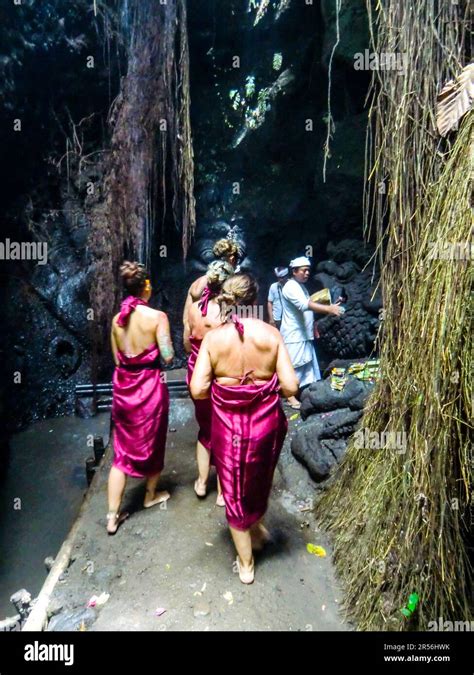 Bali Hinduism, devout people praying in Taman Beji Griya Waterfall with Brahmin priest in white ...