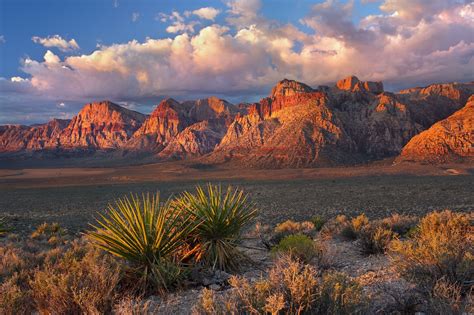 the mountains are covered in vegetation and clouds above them, as the sun is setting