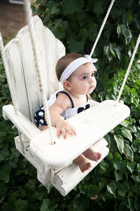 a baby sitting on a white wooden swing