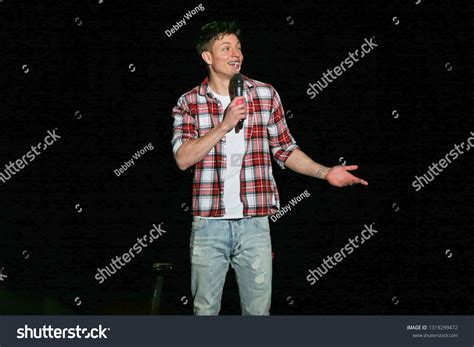 a man in plaid shirt and jeans standing on stage with his hands out to ...