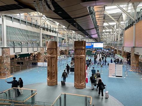 people are walking around in an airport lobby with large columns and blue carpeted flooring