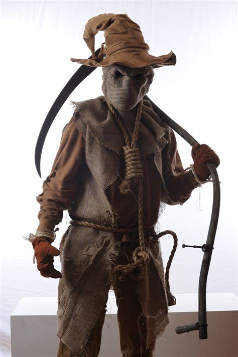 a scarecrow dressed in an old fashioned outfit holding a stick and ...