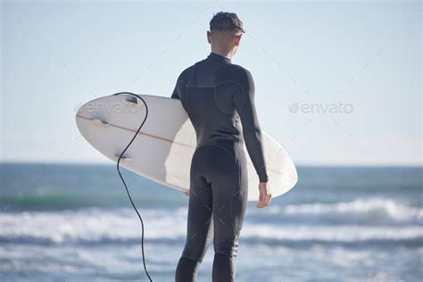 Back, surfing man and standing at beach with board, freedom and summer waves with blue sky ...