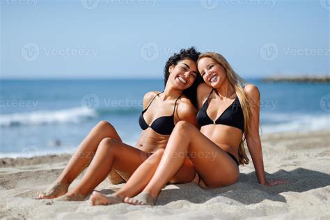 Two young women with beautiful bodies in swimwear on a tropical beach ...