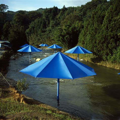 there are many blue umbrellas that are in the water near some trees and bushes