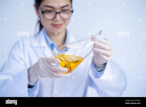 laboratory researcher holding medical glass bottle with yellow liquid, Scientist woman at job ...
