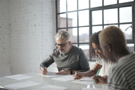 Focused diverse colleagues writing on papers with pen in office · Free ...