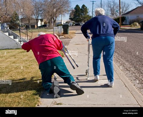 Two elderly senior citizens walk away using walkers, the woman tripped ...