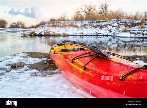 winter kayaking in Colorado - red whitewater kayak with a paddle on shore of St Vrain Creek ...