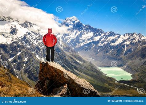 Happy Free Tourist Man Standing Outstretched Up Looking at River and Mountains Landscape from ...