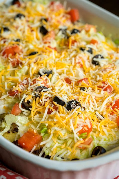 a casserole dish with cheese, olives, tomatoes and other toppings