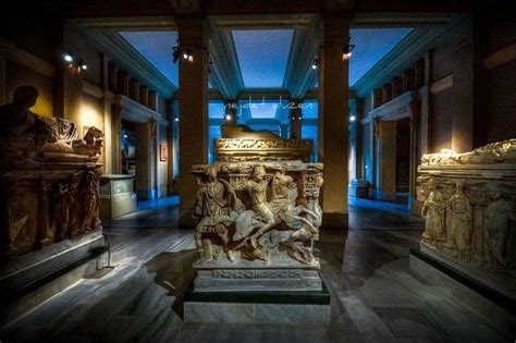 some statues are on display in a room with blue light from the ceiling and windows