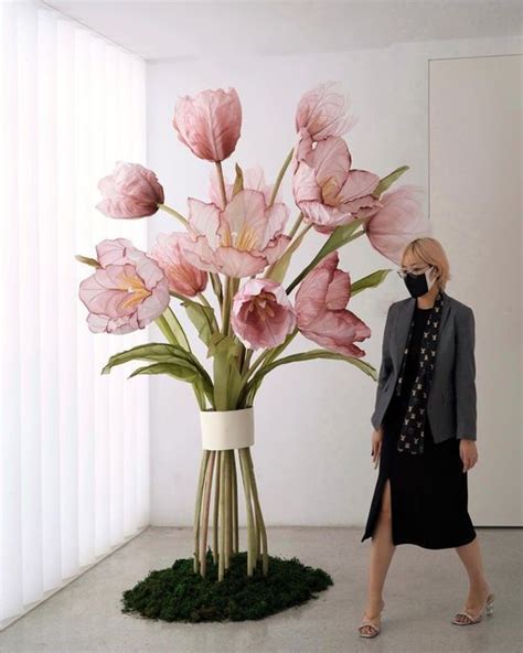 a woman standing next to a vase with pink flowers