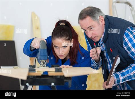 carpenter with female apprentice cutting wood in workshop Stock Photo - Alamy