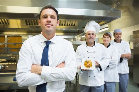 Young restaurant manager posing in front of team of chefs — Stock Photo © Wavebreakmedia #33443549