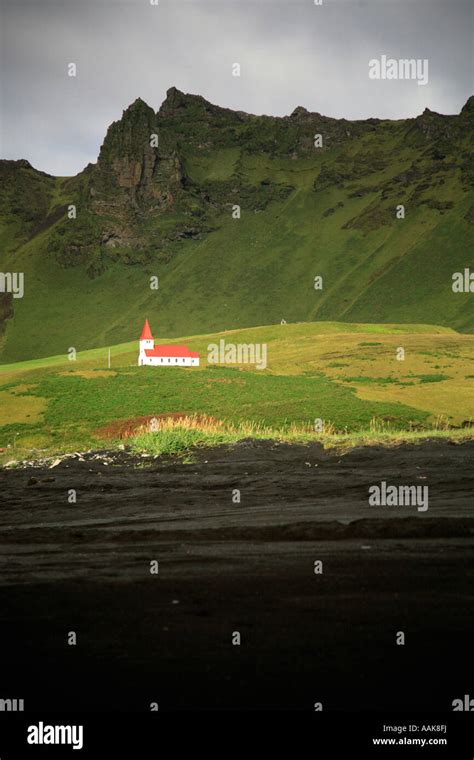 White church on the hill from the black volcanic beach Iceland Stock Photo - Alamy