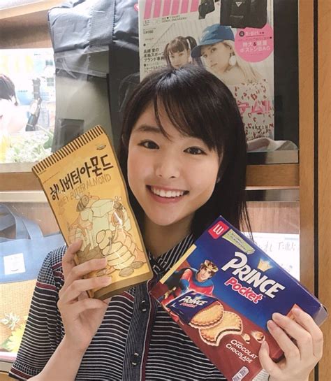 a woman holding up some snacks in front of her face and smiling at the camera