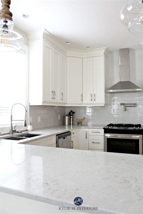 Low contrast white kitchen with Bianco Drift quartz countertops and gray subway tile backsplash ...