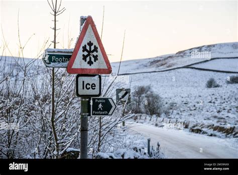 Ice warning sign on an untreated minor road in England, UK, in very cold winter conditions. Snow ...