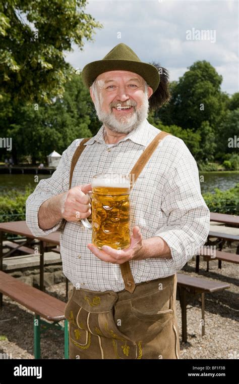 A traditionally clothed German man in a beer garden holding a beer ...