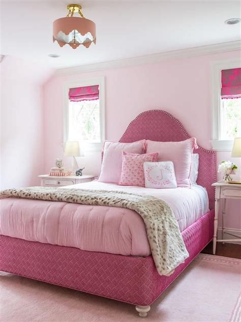 Super pink girl's bedroom features a pink pendant light illuminating a bed with arch headboard ...