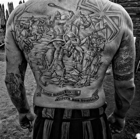 the back of a man with tattoos on his chest and arms, holding a baseball bat